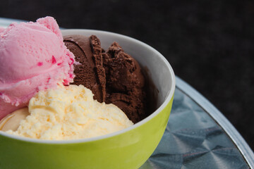Bowl of various flavors of ice cream on top of a metal table.