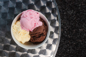 Top view of a bowl of different flavors of ice cream on a metal table.