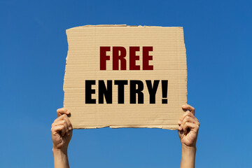 Free entry text on box paper held by 2 hands with isolated blue sky background. This message board...