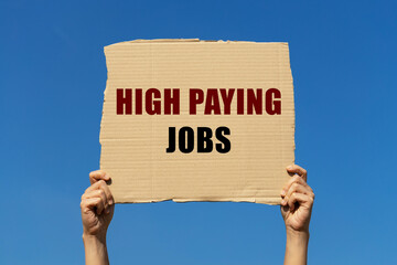 High paying jobs text on box paper held by 2 hands with isolated blue sky background. This message board can be used as business concept about high paying jobs.