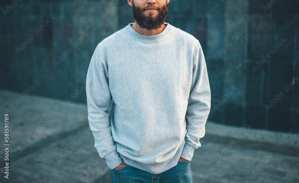 Wall mural city portrait of handsome hipster guy with beard wearing gray blank hoodie or hoody and hat with spa - Wall murals