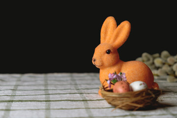 Easter bunny with Easter eggs in the nest. Willow branches on the background. Space for text. Beautiful greeting card. Easter concept. Easter decorations
