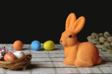 Easter bunny with Easter eggs in the nest. Willow branches on the background. Space for text. Beautiful greeting card. Easter concept. Easter decorations
