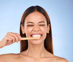 Toothbrush, toothpaste and cleaning with a woman in studio on a blue background for oral hygiene. Mouth, dentist and dental with an attractive young female brushing her teeth for healthy gums