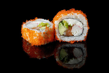 Sushi roll with salmon, cream cheese, crab, avocado and flying fish roe, on a black