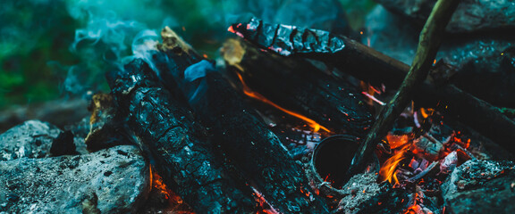 Vivid smoldered firewoods burned in fire close-up. Atmospheric warm background with orange flame of...