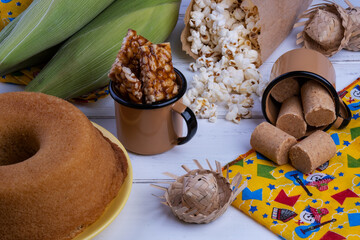 green corn and sweets from festa junina on white wooden table
