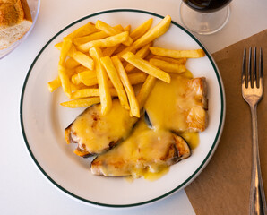 Cooked swordfish in hollandaise sauce with french fries closeup