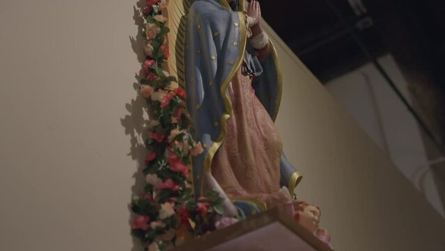 This panning video shows a side view of a beautiful Virgin Mary statue displayed on a cathedral wall. 