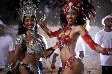 Turning beats into heat. two beautiful samba dancers performing in a carnival with their band.