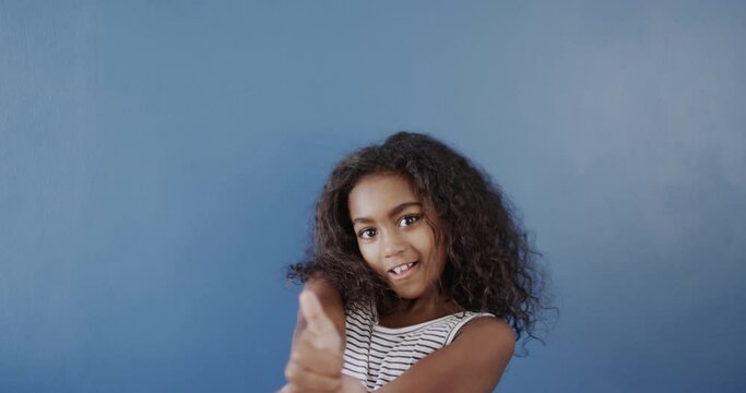 Happy african american girl using sign language on blue background, slow motion