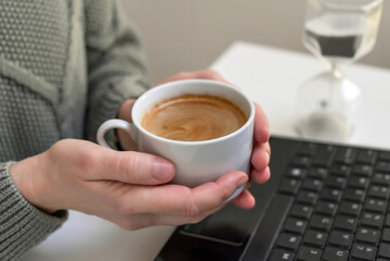 Woman drinking coffee and using digital tablet, laptop