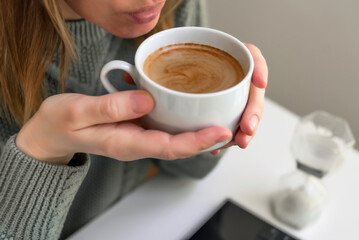 Woman drinking coffee and using digital tablet, laptop