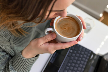 Woman drinking coffee and using digital tablet, laptop