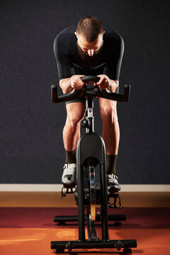 Athlete training on an exercise bike. A man with a beard in sportswear pedals on an exercise bike
