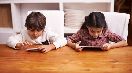 They each have their own tech toy. two siblings playing with their digital devices at home.