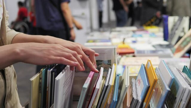 Hands choosing comics, child selecting book while visiting bookshop, kid boy searching and looking for a fairy tale book in bookstore or choose a book from a bookshelf in a