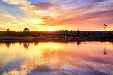 lake at sunset with beautiful reflection with windmill and clouds of colors, monte escobedo zacatecas