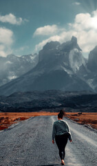 Fototapeta premium Girl Walking On Dirt Road In The Wind Towards Mirador Los Cuernos, Torres Del Paine, Patagonia,Chile