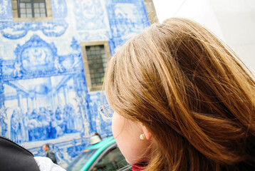 Side view of woman sightseeing Portugal with magnificent facade of a house church covered with Azulejos - a form of Spanish and Portuguese painted tin-glazed ceramic tilework