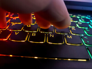 Typing on a colorful gaming laptop keyboard
