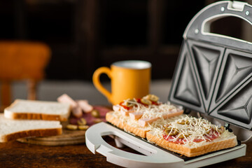 open sandwich maker with cheese toast and sausages. Sandwiching.