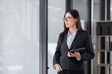 Portrait of Young business asian woman using tablet, standing in office.
