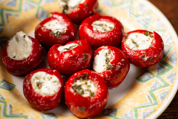 cherry tomatoes stuffed with cheese and spices on a plate.