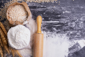 Flour and wheat grains in sacks with wheat ears On a black background table. In a rustic kitchen. Top view.
