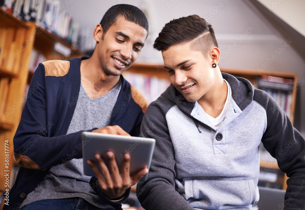 Poster youve got to check this out. two young men looking at a digital tablet in the university library.