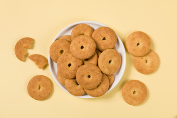 Group of tasty cookies or biscuit in plate on yellow background.