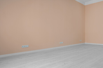 Pale orange walls with power outlet sockets in empty room