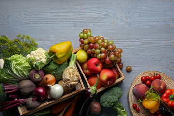 Different fresh vegetables and fruits in crates on grey wooden table, flat lay. Farmer harvesting