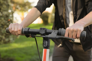 Man riding modern electric scooter in park, closeup