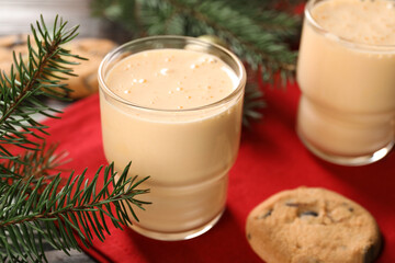 Tasty eggnog, cookies and fir branches on wooden table, closeup