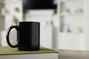 Blank ceramic mug and book on wooden table. Mockup for design - obrazy, fototapety, plakaty