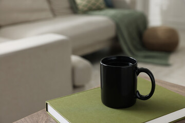 Ceramic mug of tea and book on wooden table. Mockup for design - obrazy, fototapety, plakaty
