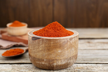 Bowl with aromatic paprika powder on old wooden table