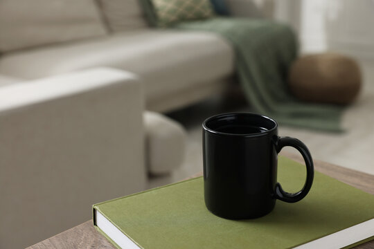 Ceramic mug of tea and book on wooden table. Mockup for design