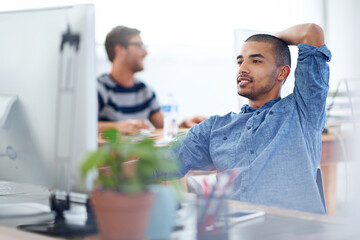 Obraz premium Another project done and dusted. a young designer working on a computer at a desk in an office.