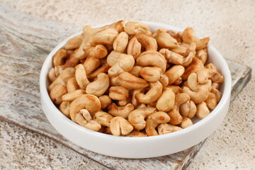 Tasty cashew nuts in bowl on white table
