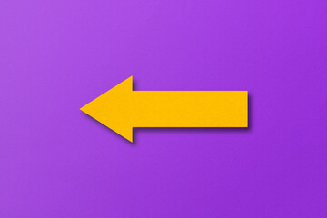 yellow paper arrow isolated on purple paper background