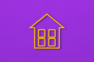 Yellow paper cut out house shape isolated on purple paper background.