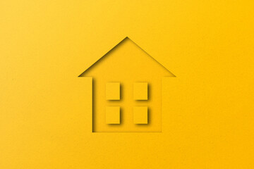 Yellow paper cut out house shape isolated on yellow paper background.
