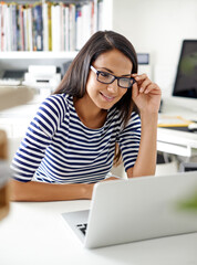 Things are looking good for her business. a beautiful young woman using her laptop in her home office.