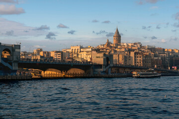 View of Beyoglu district with Galata Tower and Galata Bridge in the foreground from the waters of the Golden Horn Bay on a sunny day, Istanbul, Turkey