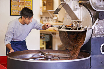 Beginning the journey to your cup. a machine grinding and roasting coffee beans.