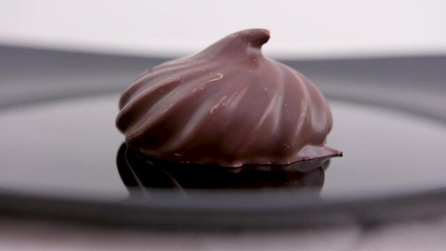Delicious chocolate covered marshmallow isolated on white. a woman's hand takes a marshmallow in chocolate from a black plate High quality photo