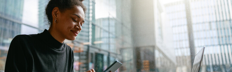 Smiling woman holding phone during working day in cafe sitting near window. Distance work concept