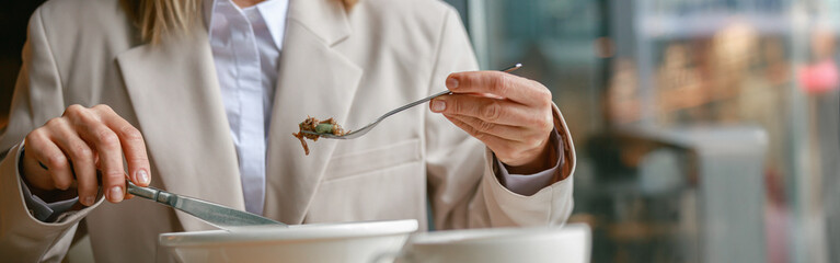 Close up of businesswoman is having a business lunch during working day in cafe. Blurred background